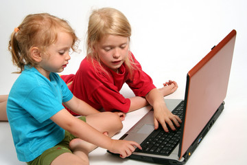 Two little girls playing on laptop 