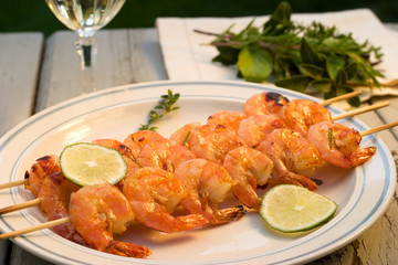 Grilled shrimps on bamboo sticks with glass of white wine