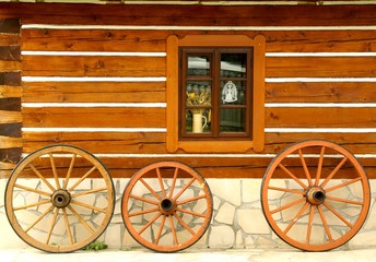 Obraz premium Wooden wheels at cottage wall