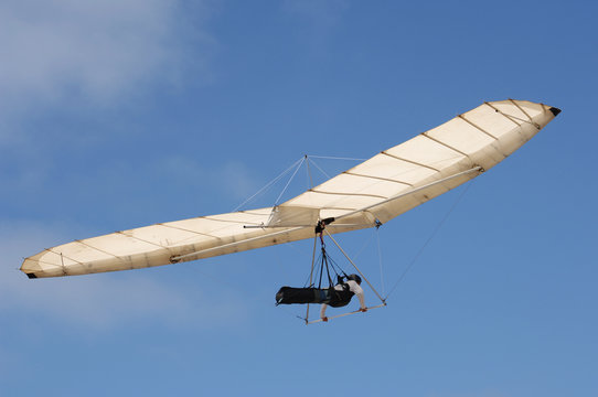 Fixed wing hang glider and pilot against a blue sky