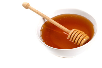 Bowl of amber honey with a honey wand isolated on white