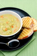 A bowl of pea and ham soup, with fresh toasted sourdough bread.