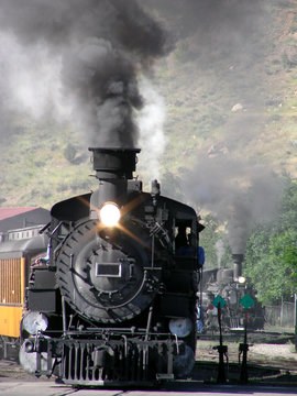Twin narrow gauge steam locomotives rounding the bend