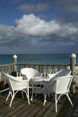 deck by the sea with wicker chairs table blue sky beach