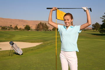 A pretty woman golfer retrieving her ball from the hole