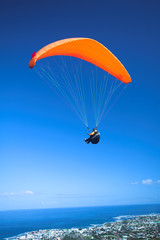 Paraglider launching from the ridge with an orange canopy 