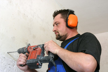 Worker with protective soundproofing ear muffs on.