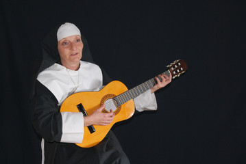 Middle aged nun playing the guitar.  Religion, 
