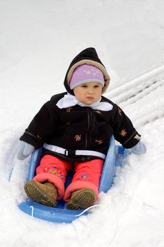 A toddler girl bewildered by her first ride in a snow.