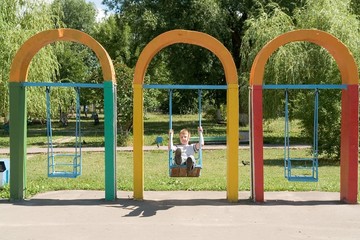 little boy on a swing in city park