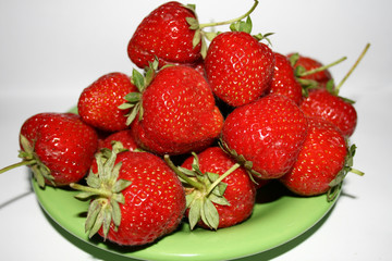 The ripe red strawberry on the plate.