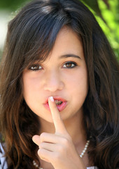 A pretty teenage girl doing be quiet gesture