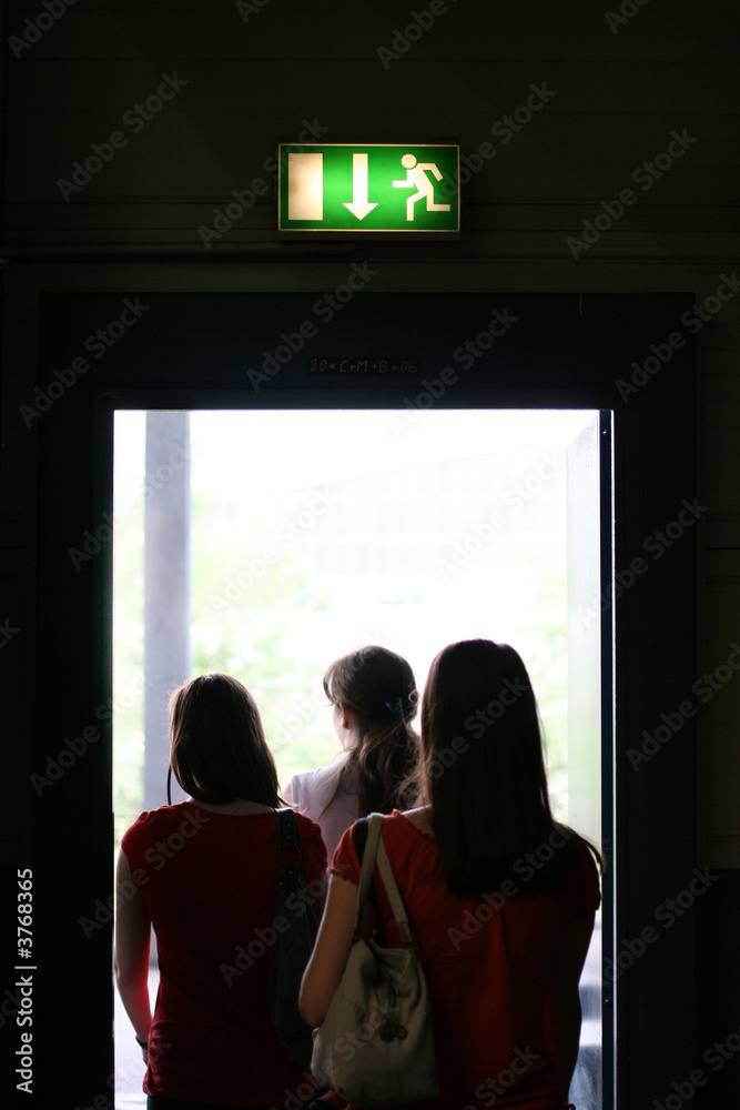 Wall mural three girls exit the building on exit door. exit symbol