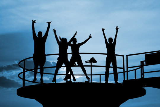 Happy people jump silhouettes on blue sky. Happiness concept