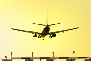photo of an aeroplane landing at sunset