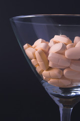 Pills in a martini glass - Drug abuse concept.