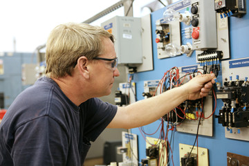 A vocational education teacher wiring a motor control board