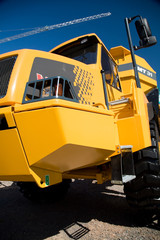 Yellow construction dumper truck against blue sky