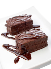 Two chocolate cupcakes on white plate with syrup. Shallow DOF