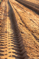 Dusty gravel road with tyre imprints , shot at sunset