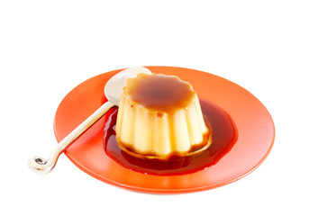 Cream caramel on red plate with spoon shot on white background