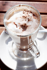 A cup of cafe latte with a spoon next to it