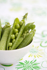 Fresh peas in white bowl, shallow focus