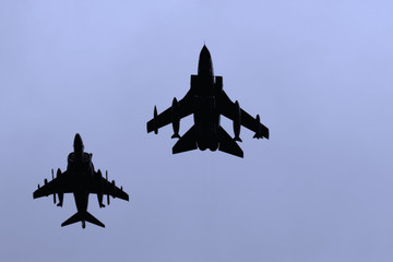 A pair of RAF  jet fighters silhouetted against a blue sky. Panavia Tornado and BAE Harrier