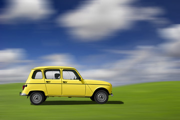 Yellow classic car at high speed in a green meadow 