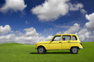Yellow classic car in a green meadow