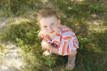 a 3 year old boy sitting on the grass