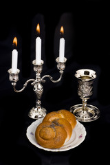Candlestick a cup and bread on a black background
