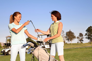 Two pretty women golfers selecting a golf club