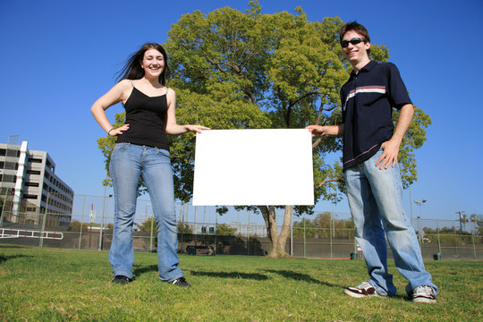 Young Couple Holding A Blank White Sign Outdoors