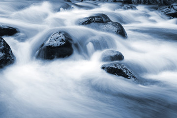 Blue stream of water flowing over rocks 