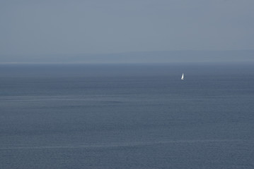 kleines weißes Segelboot in der Weite des blauen Meeres