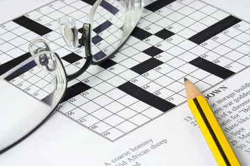 Pencil and spectacles on top of a crossword puzzle..