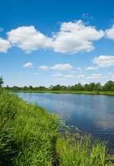 bank of the river, green grass and blue sky