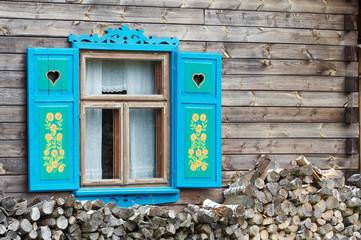 Opened window with decorative colorful shutters and logs below.. - 3829375