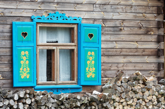 Fototapeta Opened window with decorative colorful shutters and logs below..