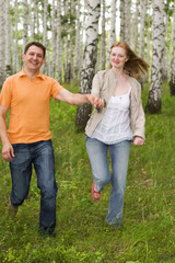 two happy people running in the forest