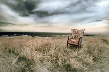 Stormy beach with wingback chair in infrared.