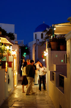 Fototapeta Nightime shoppers walk the streets of Oia, Greece.