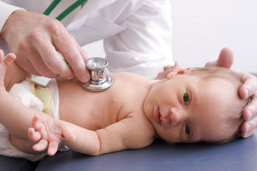 Newborn baby with a doctor listening to her heart.