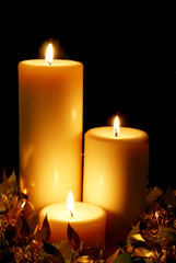 A trio of golden Christmas candles, with black background.