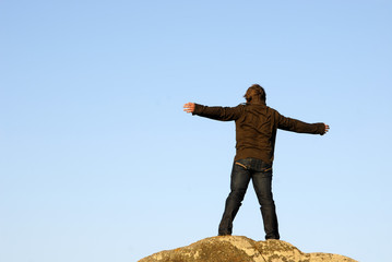 young man with arms wide open and the sky as background