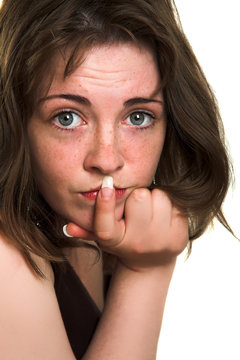 young freckled woman with finter near her lips