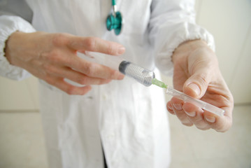 Docator holding with two hands a medical syringe