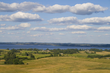 Fototapeta premium Landscape of fields and lake with clouds, captured in Latvia