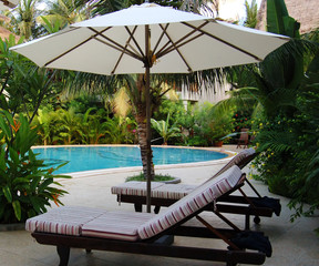 chairs under umbrella at the poolside
